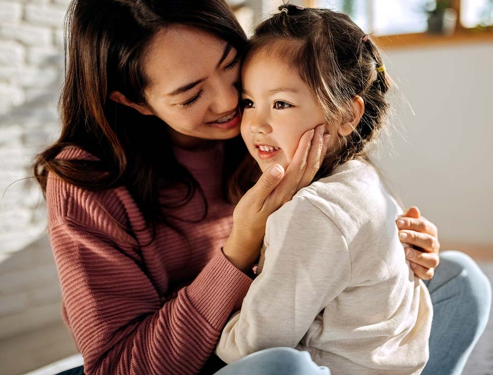 Mother and daughter hugging each other in their bed room